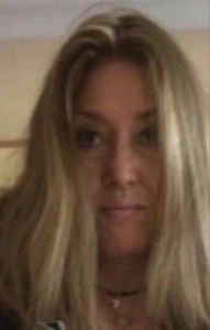 Photo portrait d'une femme blonde avec les cheveux raides, cachant légèrement ses yeux maquillés de noir.